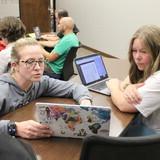 Students at a table looking at computers.